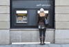a woman using an automated banking machine that is in the side of a building